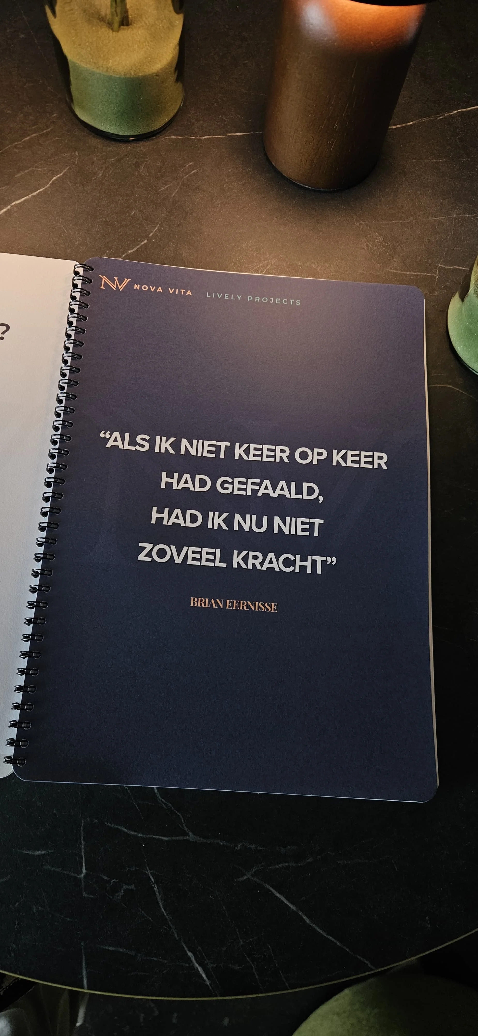 Een boek of notitiekaart met een citaat van Brian Eernisse, geplaatst op een donkere tafel met flesjes en mokken.
