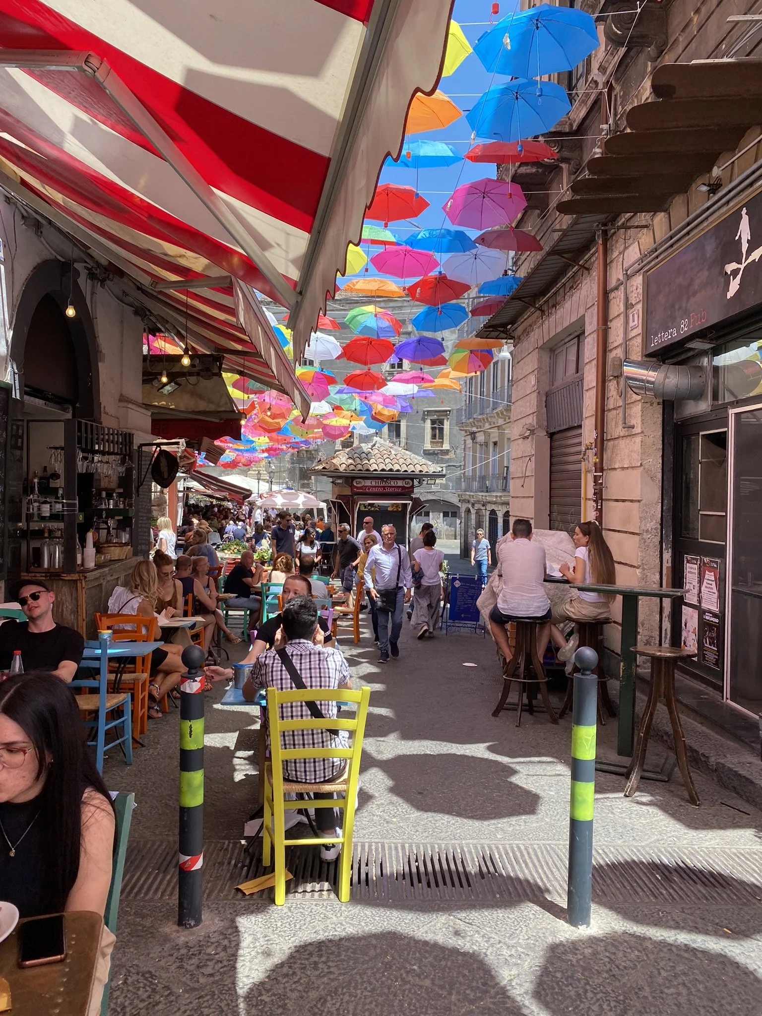 Catania, busy street with restaurants and umbrellas