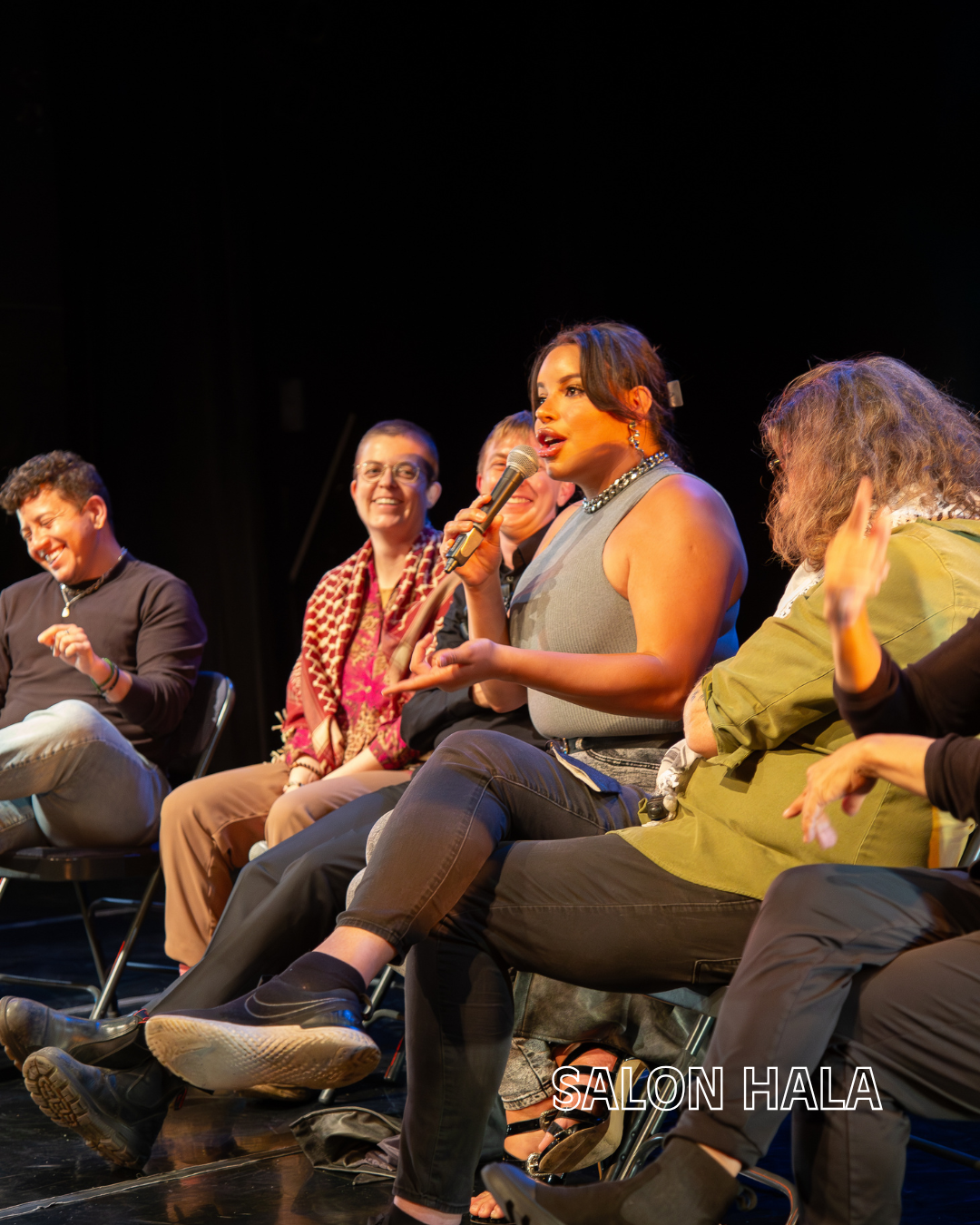 A panel of five diverse women sitting on stage at an event, one speaking into a microphone, with a dark background and stage lighting, and the words 'SALON HALA' in the lower right corner.