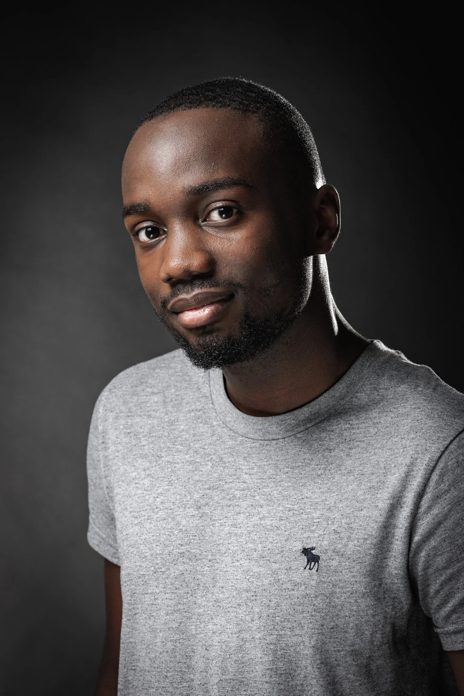 Portrait d'une personne souriante portant un t-shirt gris.