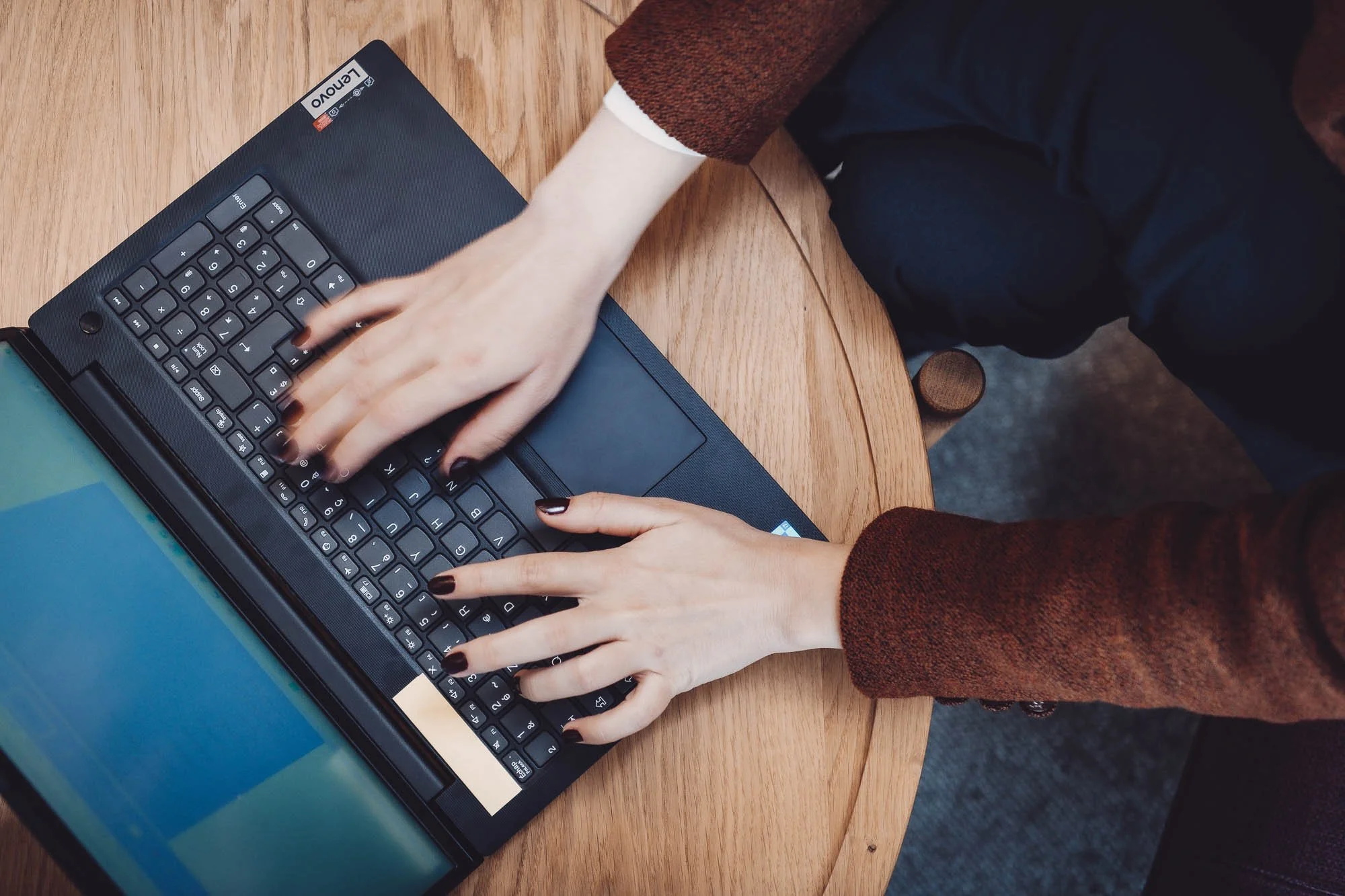 Personne utilisant un ordinateur portable noir sur une table en bois.