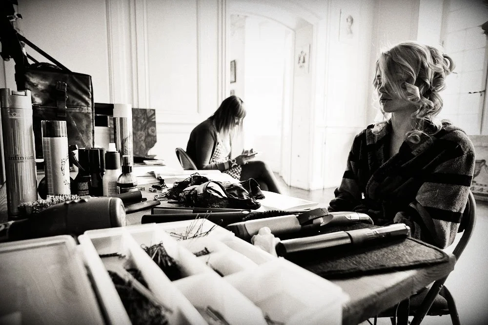 Deux femmes dans un salon de coiffure avec des produits capillaires et outils sur la table, en noir et blanc.