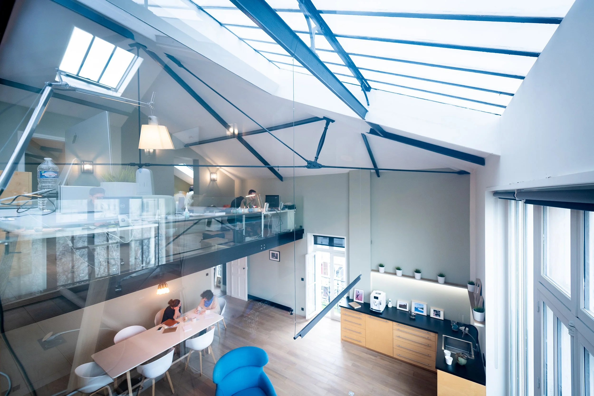 Intérieur d'un bureau moderne avec mezzanine, grandes fenêtres, et toit en verre.