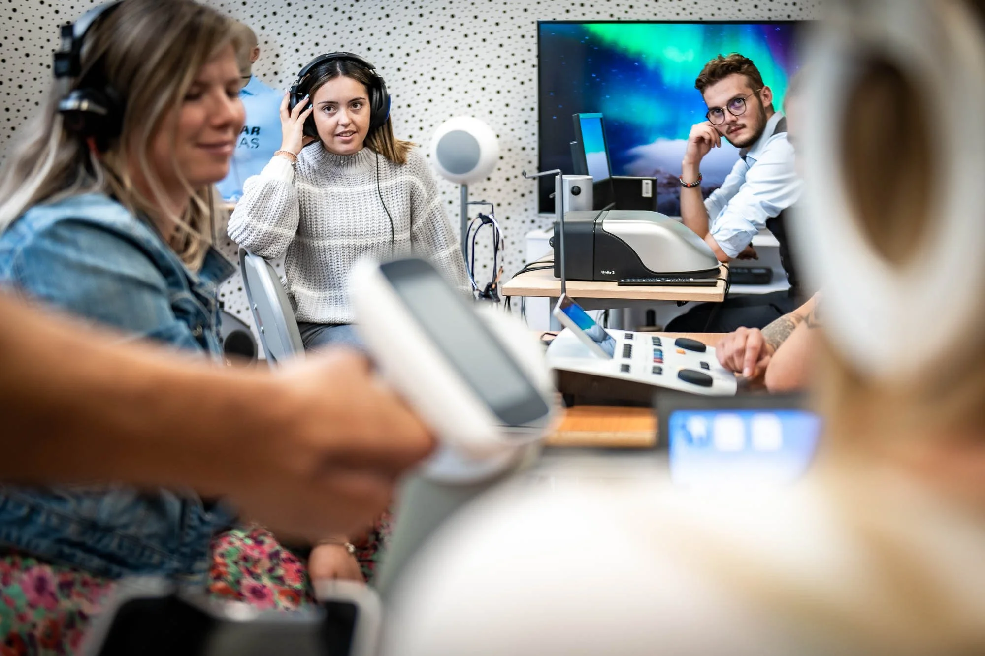 Groupe de personnes faisant des tests auditifs avec des casques dans une salle équipée de matériel audio professionnel.