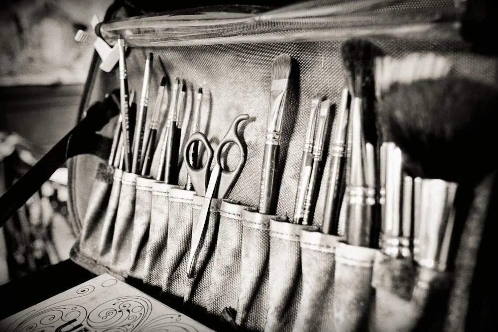 Un ensemble de pinceaux et d'outils de maquillage dans une trousse, en noir et blanc.