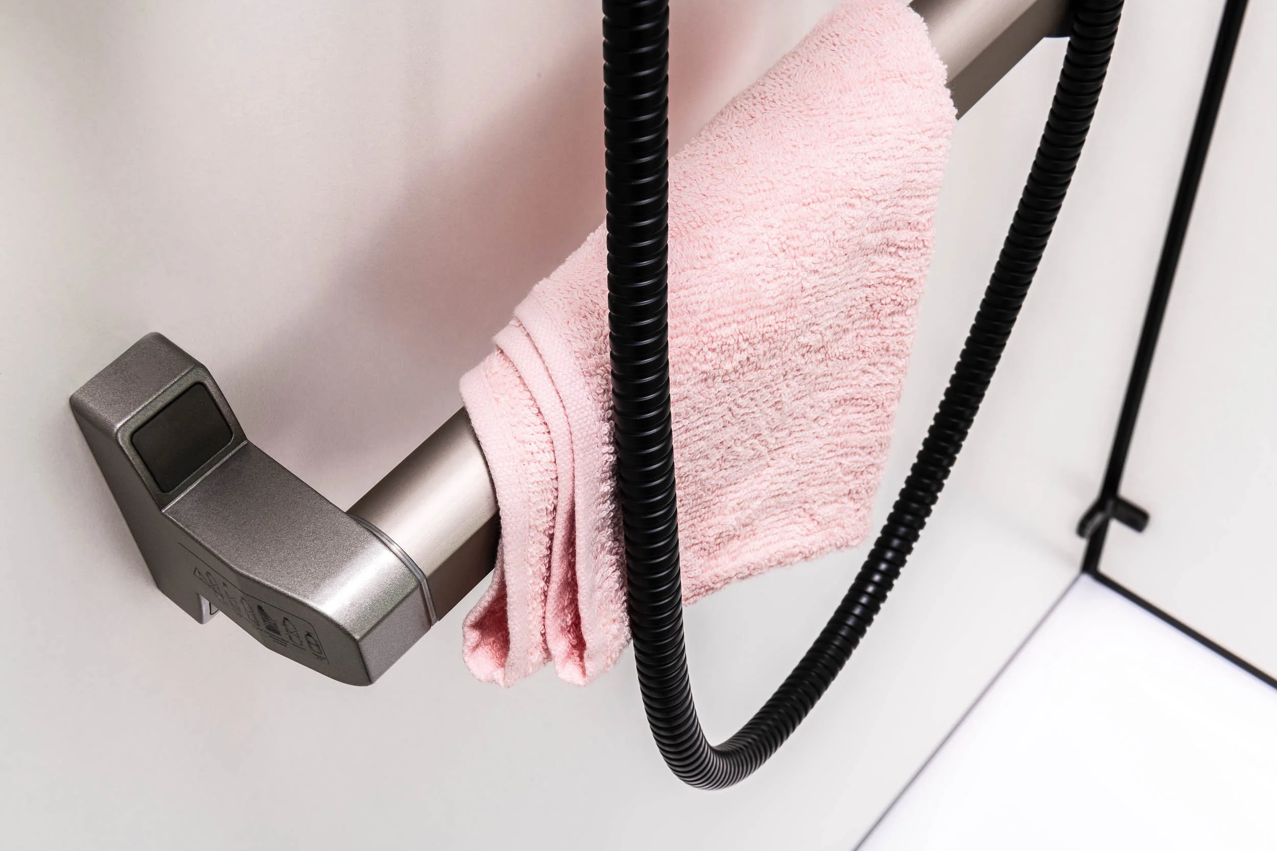 Barre d'appui de douche avec serviette rose accrochée.