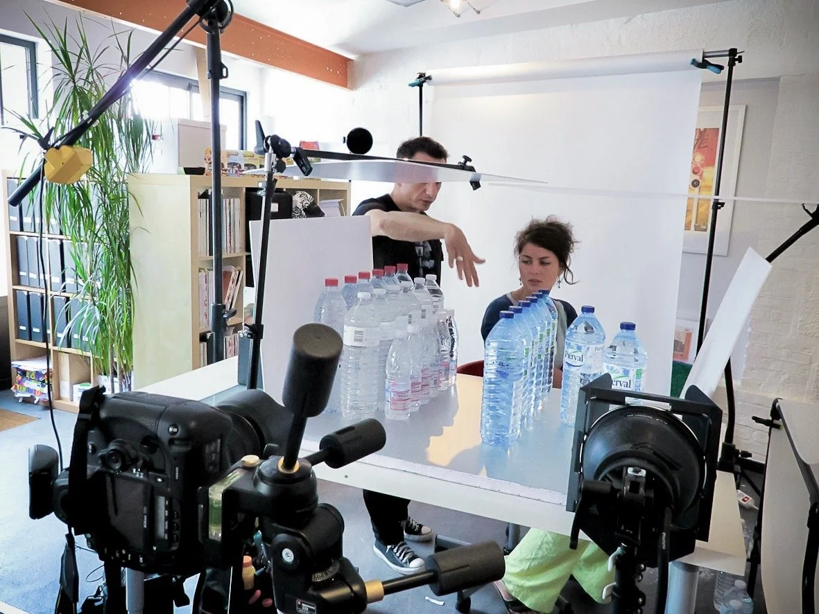 Deux personnes dans un studio photo avec des bouteilles d'eau, équipement de photographie.