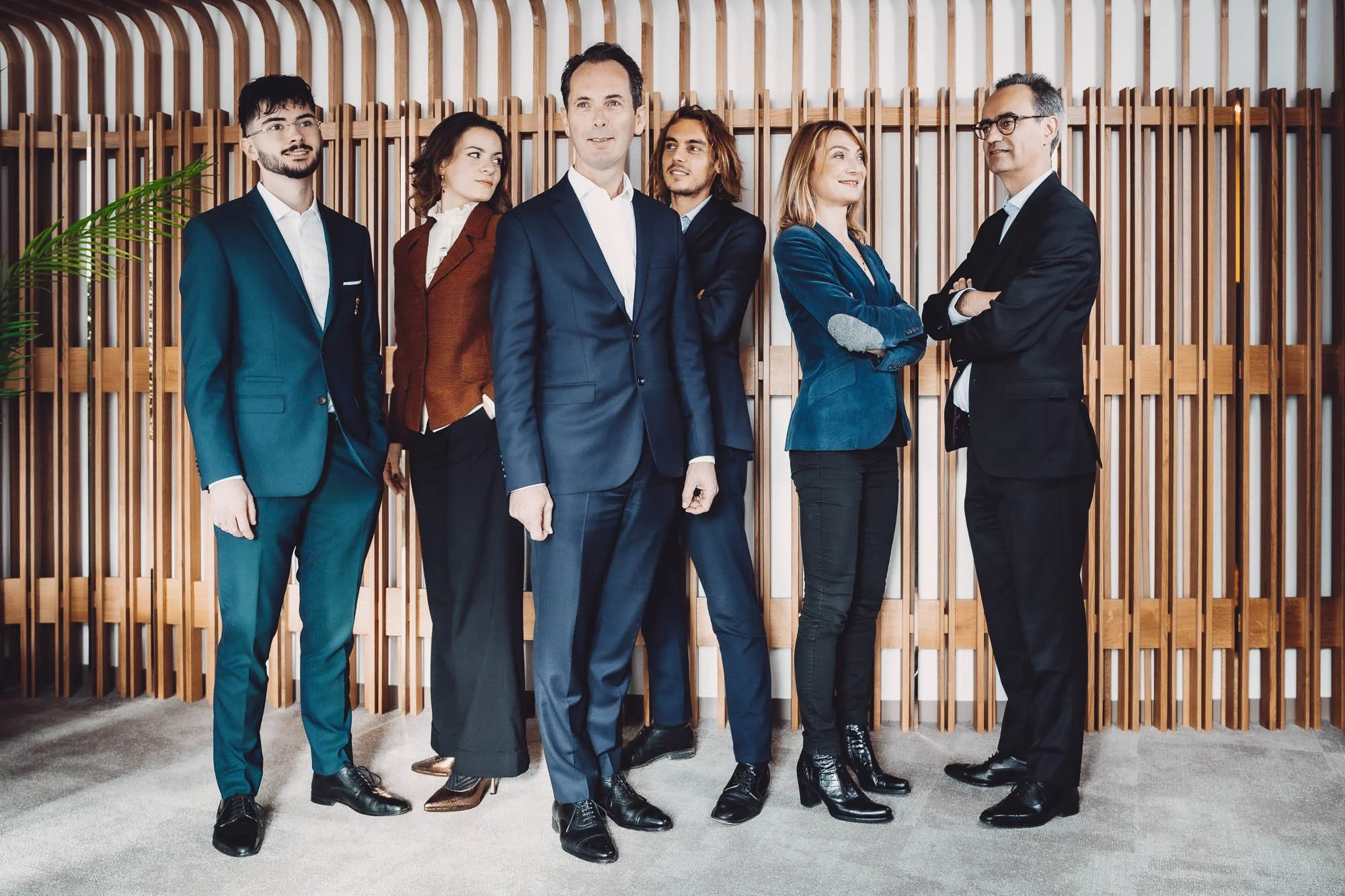 Groupe de personnes en tenue professionnelle, debout devant un mur en bois.
