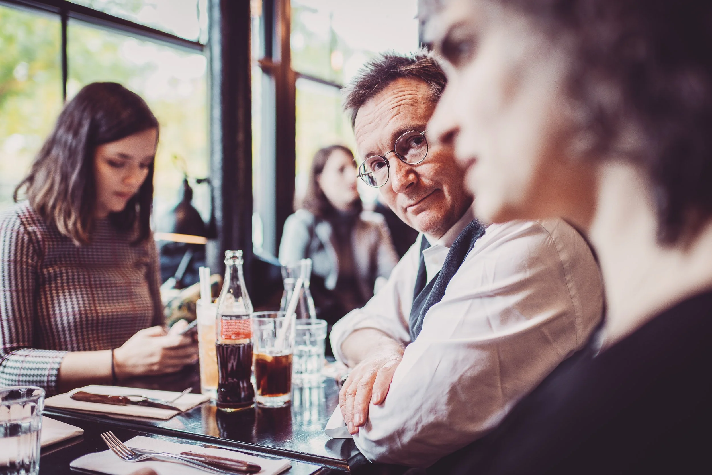 Quatre personnes assises à une table de restaurant, des boissons et des couverts devant elles.