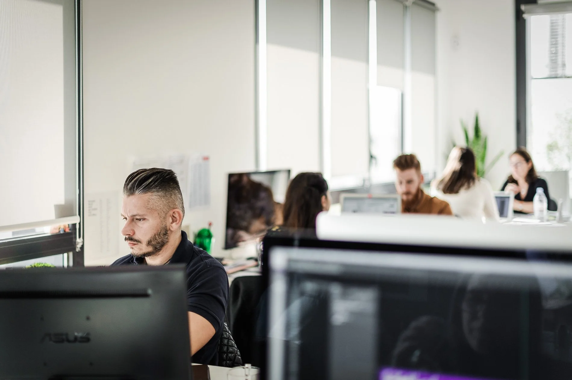 Personnes travaillant sur des ordinateurs dans un bureau moderne.
