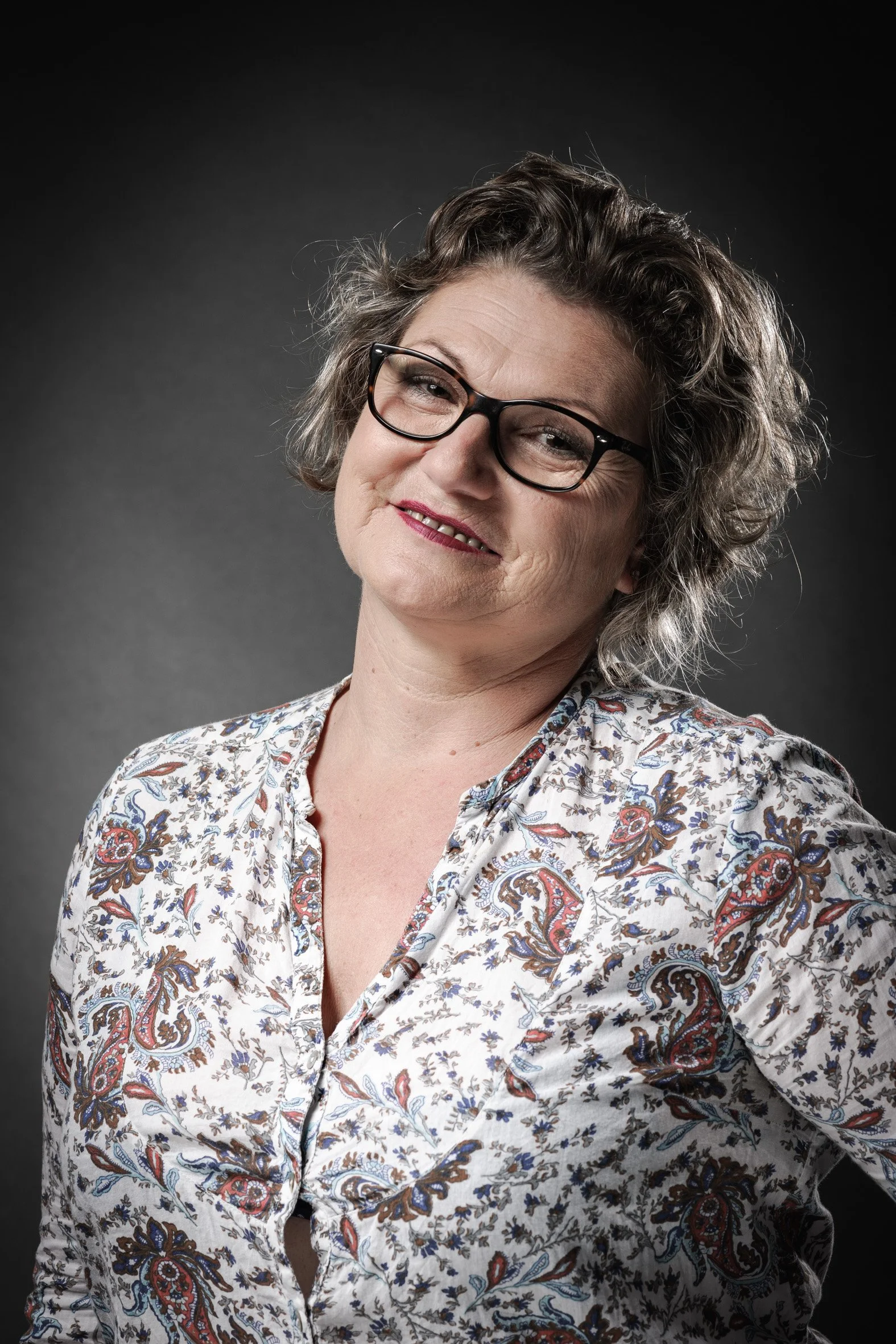 Personne portant des lunettes et une chemise à motifs, souriant.