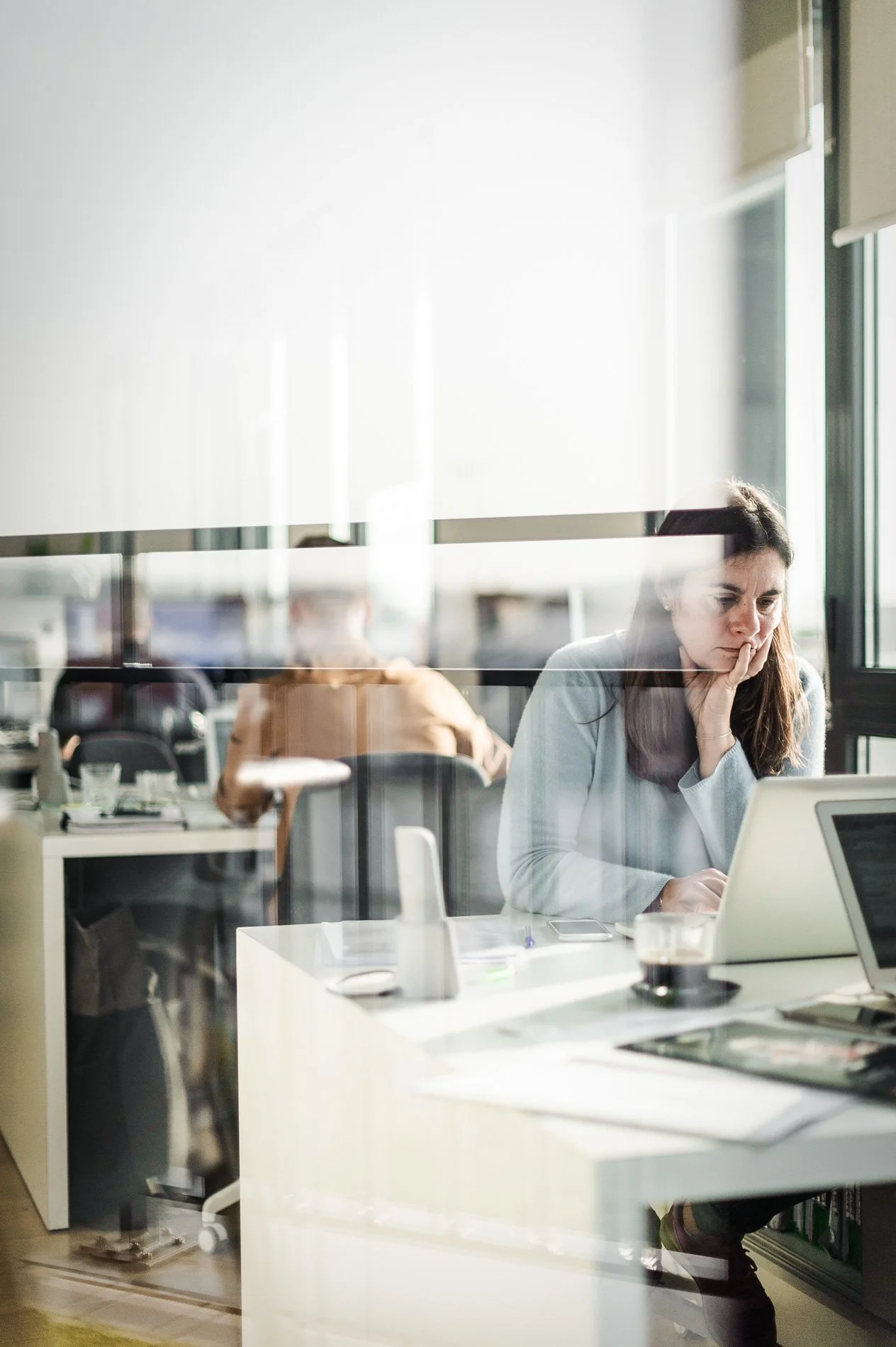 Femme travaillant sur un ordinateur portable dans un bureau moderne avec des collègues.