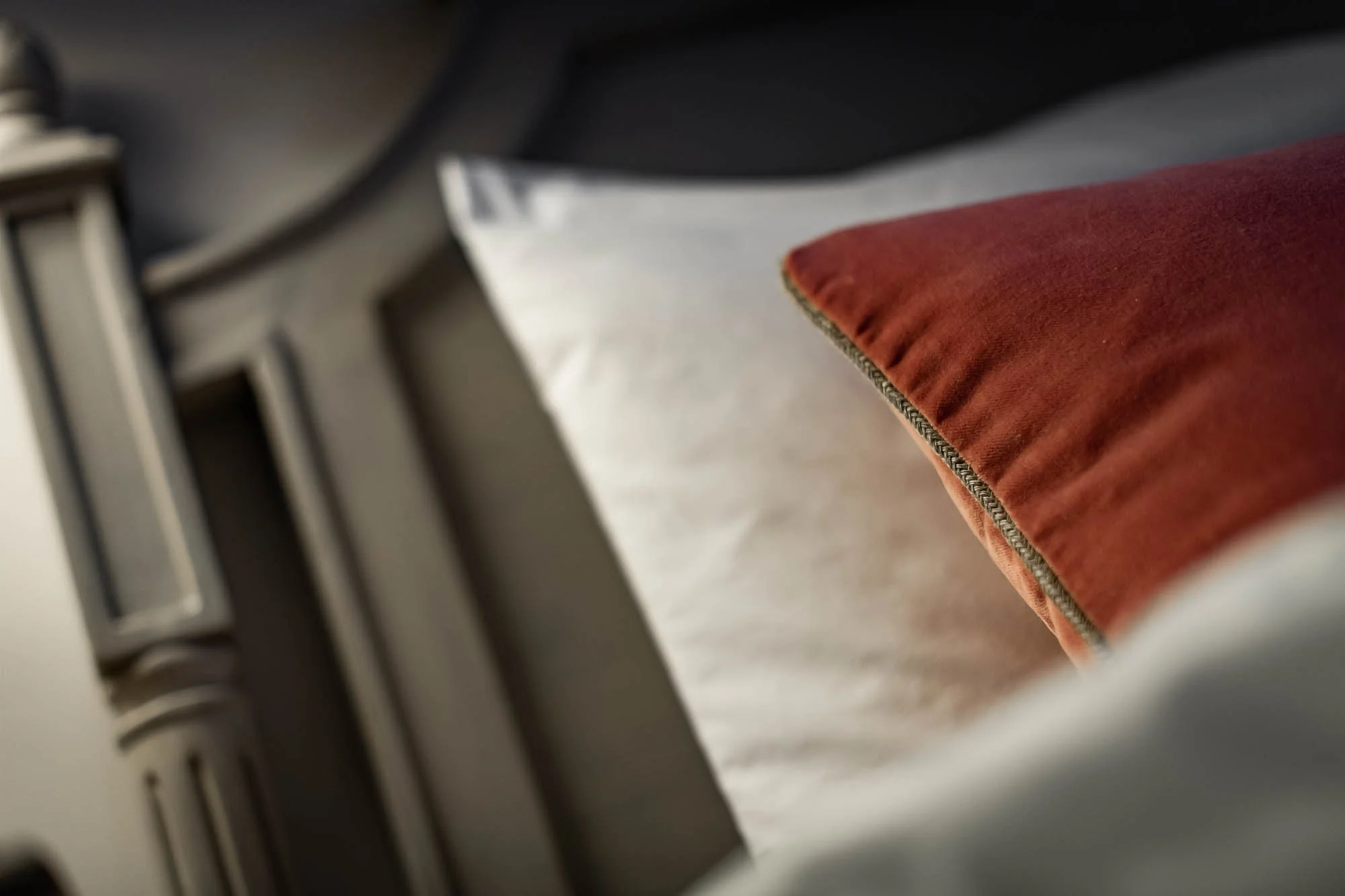 Gros plan d'un oreiller rouge sur un lit avec une tête de lit en bois.