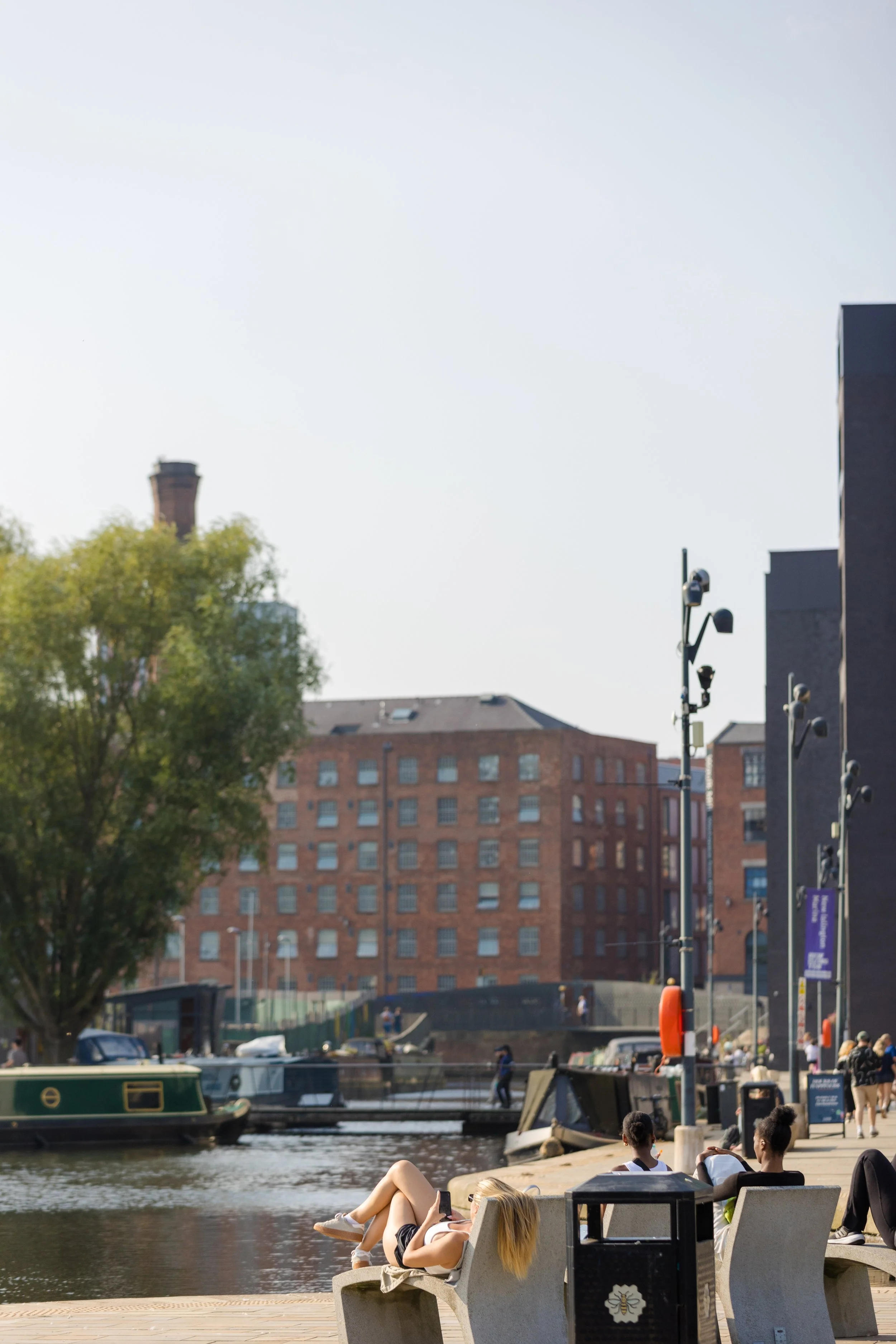 People relaxing by the canal side on a sunny day