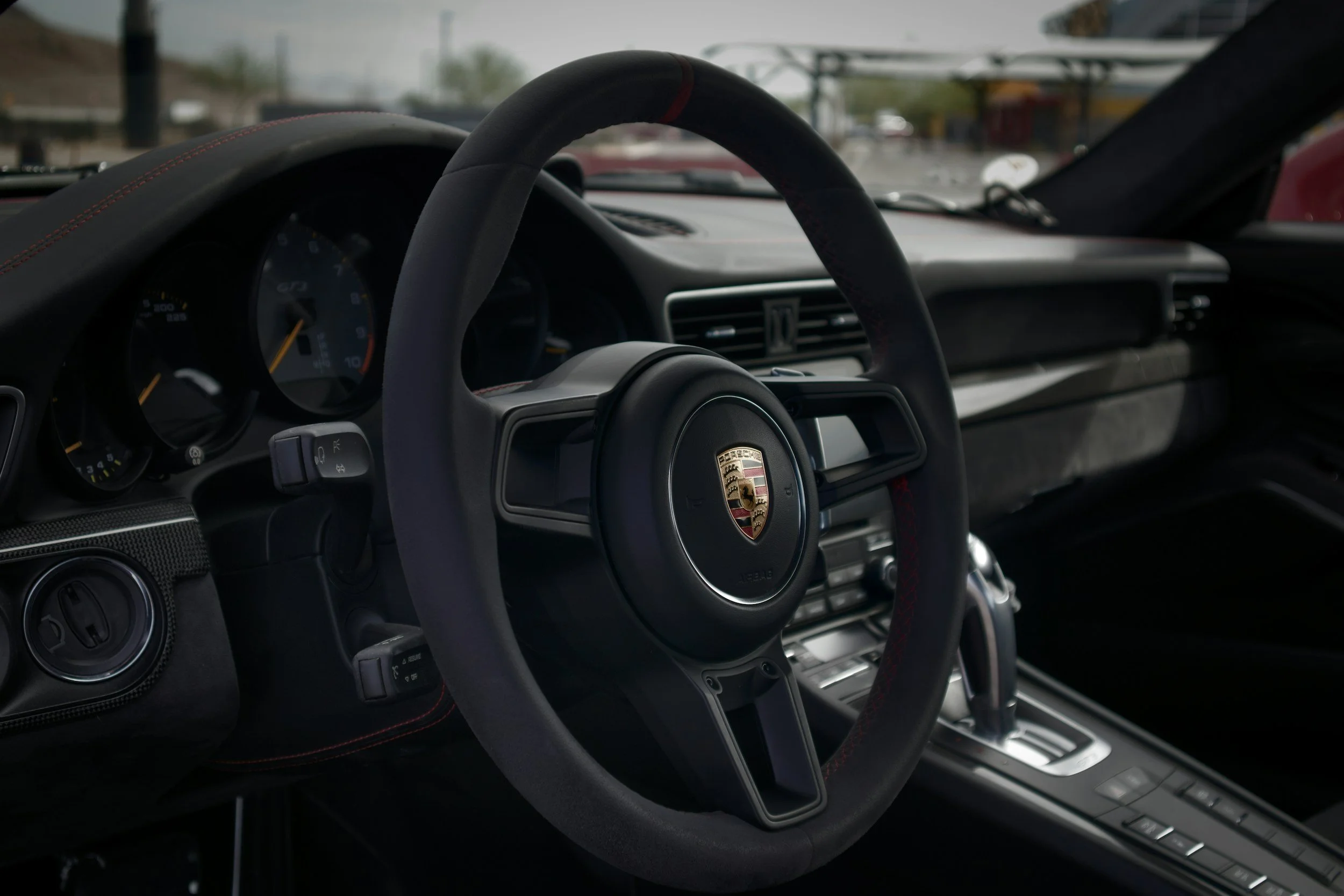 Interior of a luxury sports car showing steering wheel with logo, dashboard, and gear shift.