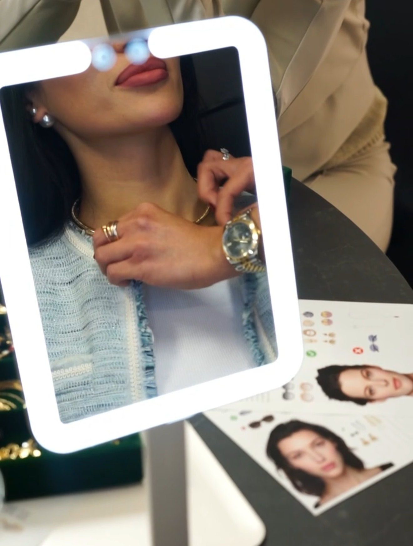 Close-up of a woman trying on jewelry in front of a mirror at a beauty store, with a makeup chart and a beauty advertisement poster in the background.