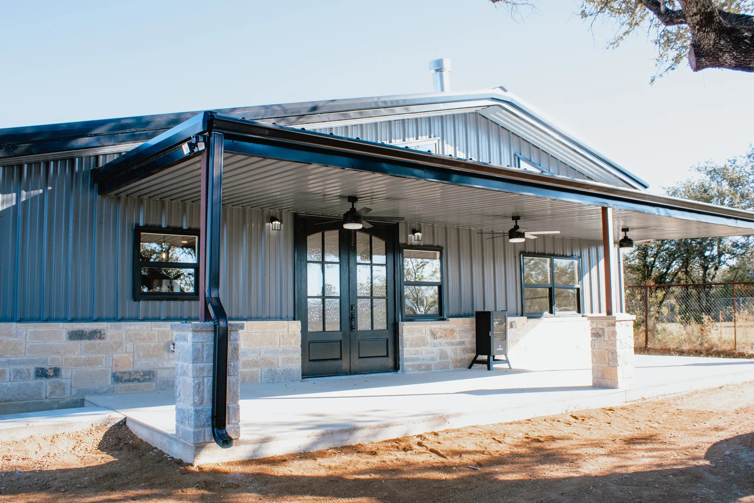 Barndominium with stone wainscot and covered porch in Kingsland, TX