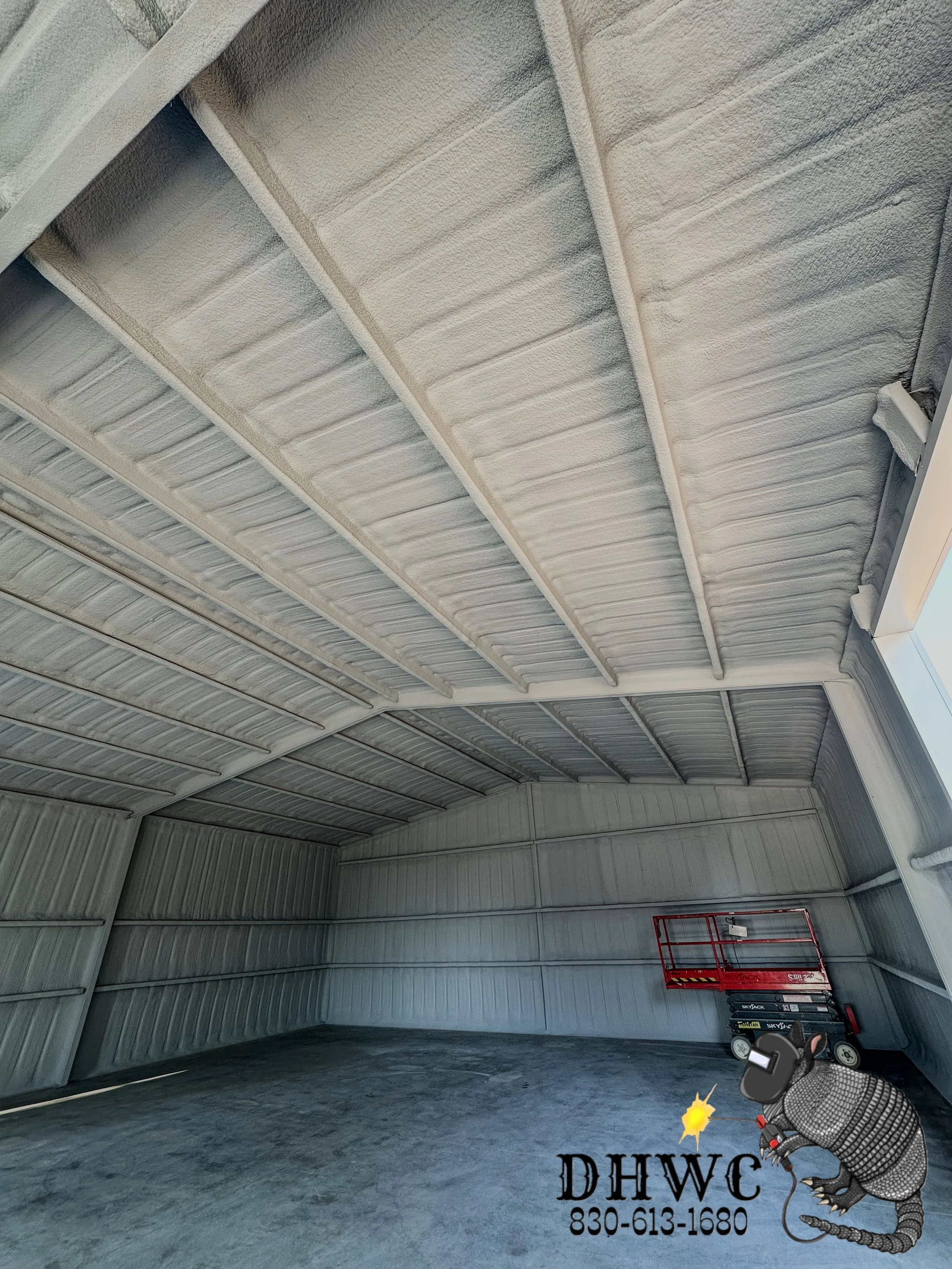 Painted spray foam insulation covering the roof and wall panels of a metal building