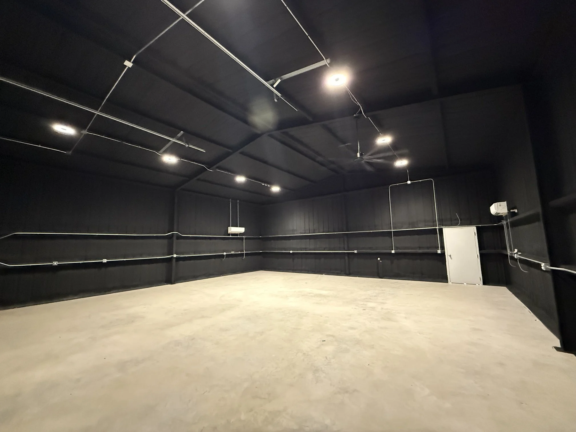 Finished metal shop interior with spray foam walls and roof painted black