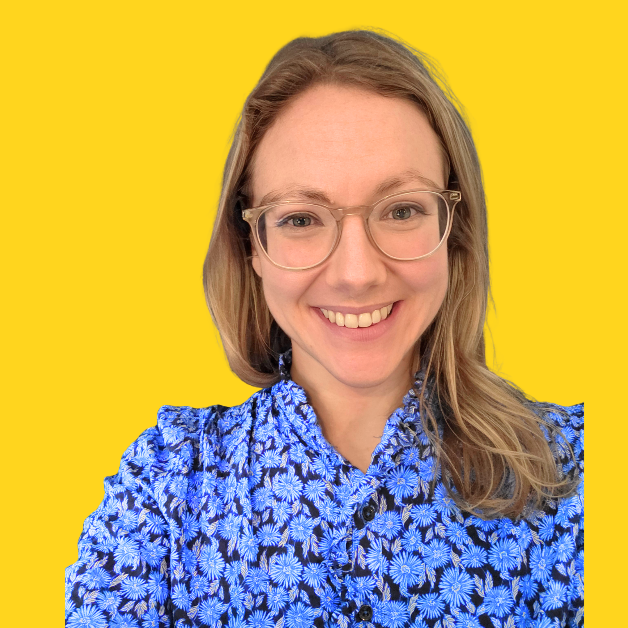 Jess is the founder of Neuro Natives a consultancy that focusses on Neuro divergent differences and Neuro Inclusion. She is a blonde woman in her thirties wearing clear glasses. She is wearing a blue and black patterned top. She is smiling.