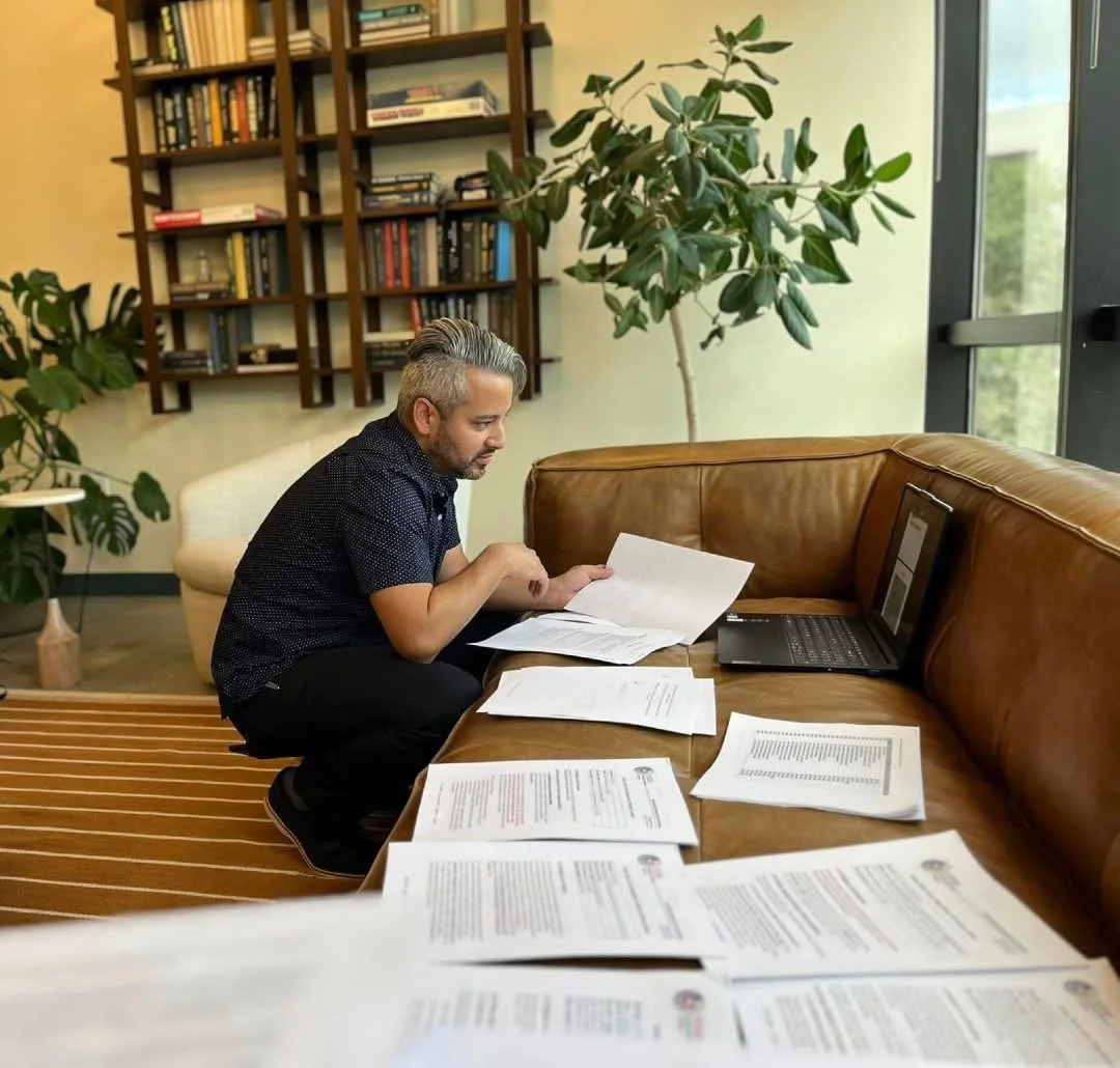 Document Review in Progress: A team member sits with multiple papers and a laptop, carefully reviewing files to ensure information is accurate and complete.