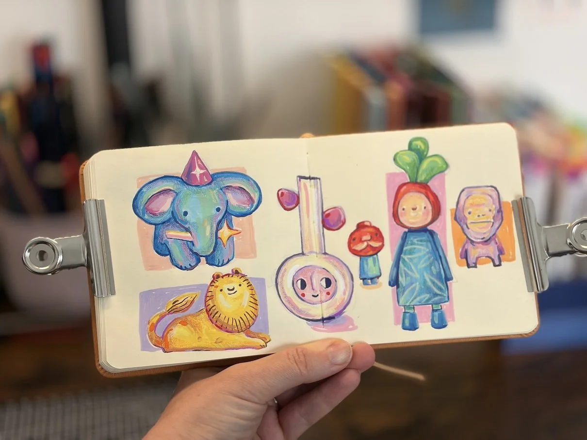 Colorful sketches of various cartoon animals and characters in a sketchbook, including an elephant with a party hat, a lion lying down, a blood sample with faces, and characters with plant and animal features.