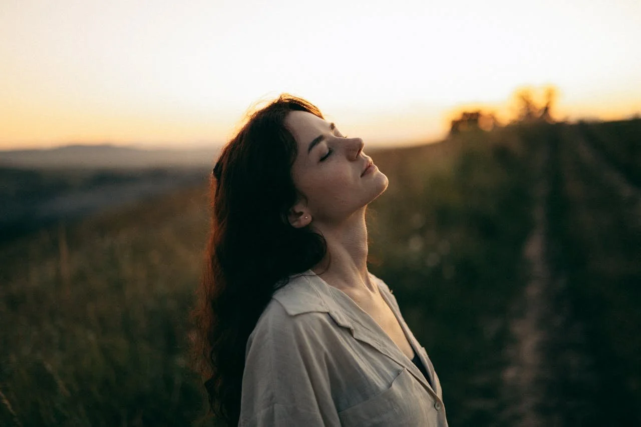 woman-standing-in-the-meadow-with-eyes-closed