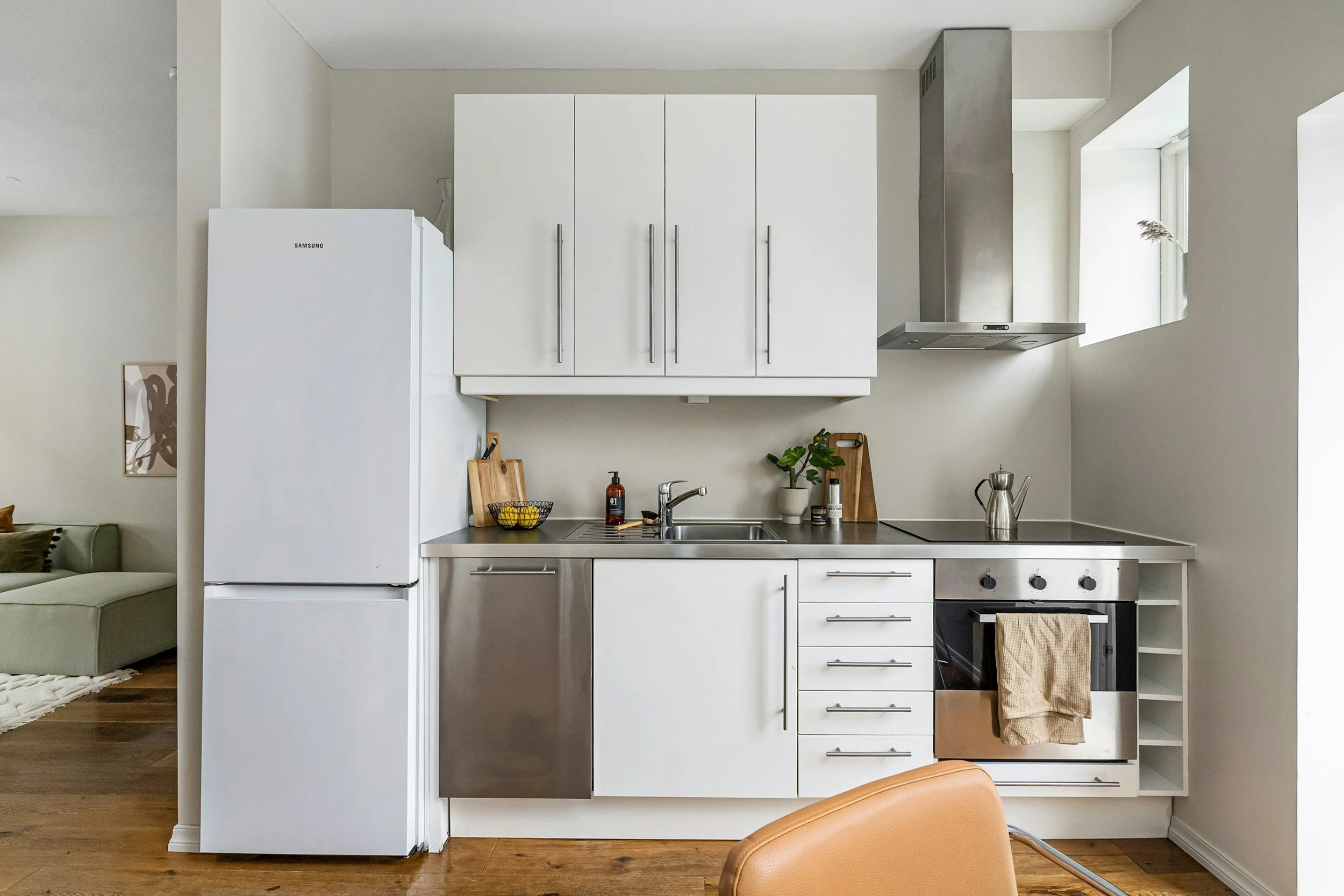 Modern kitchen with white cabinets, stainless steel appliances, a small potted plant, and wooden cutting boards.