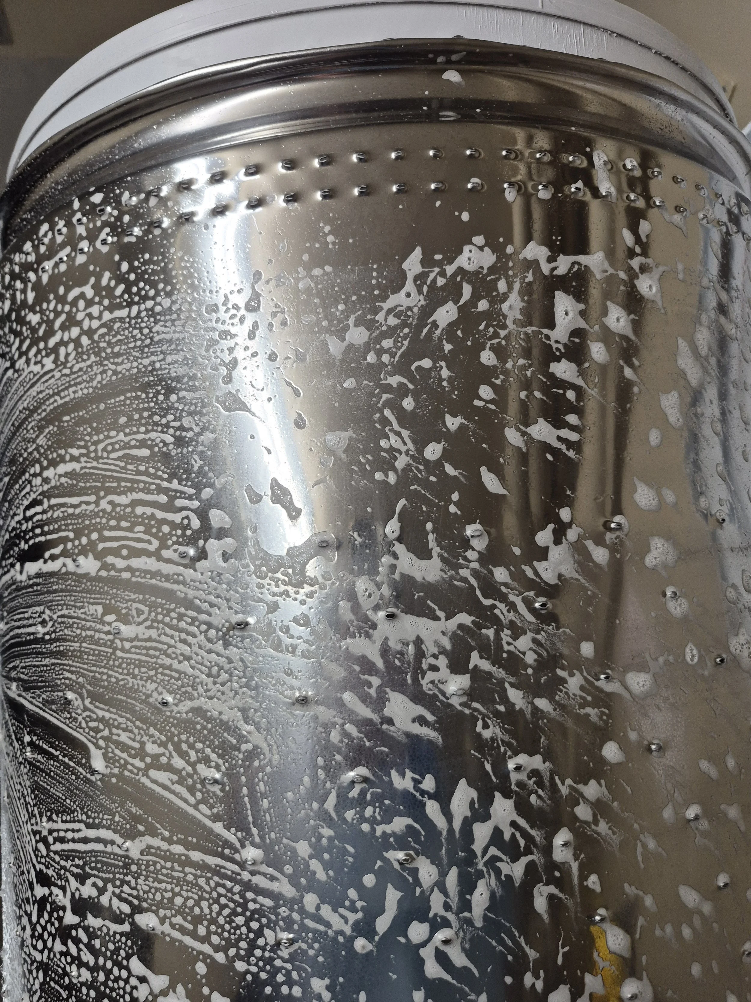 Stainless steel surface with soap suds and water droplets.