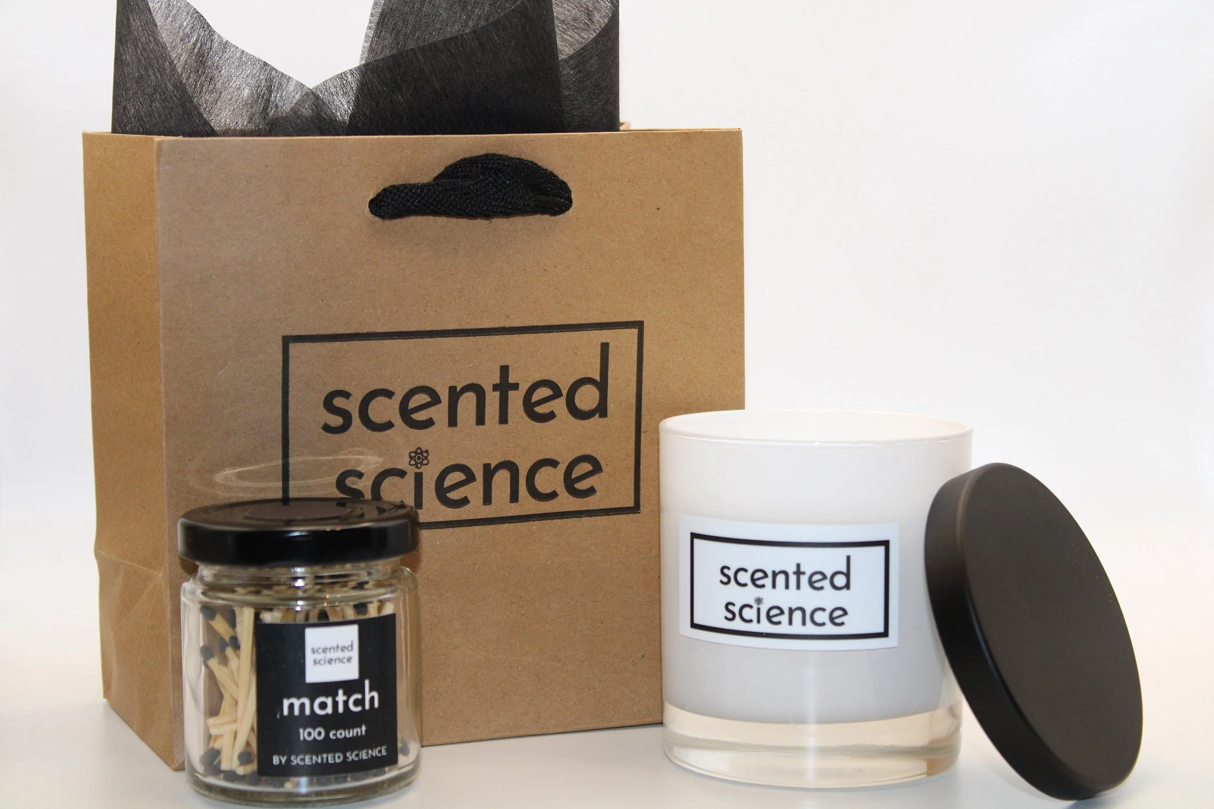 A scented candle, a jar of matches, and a gift bag from Scented Science.
