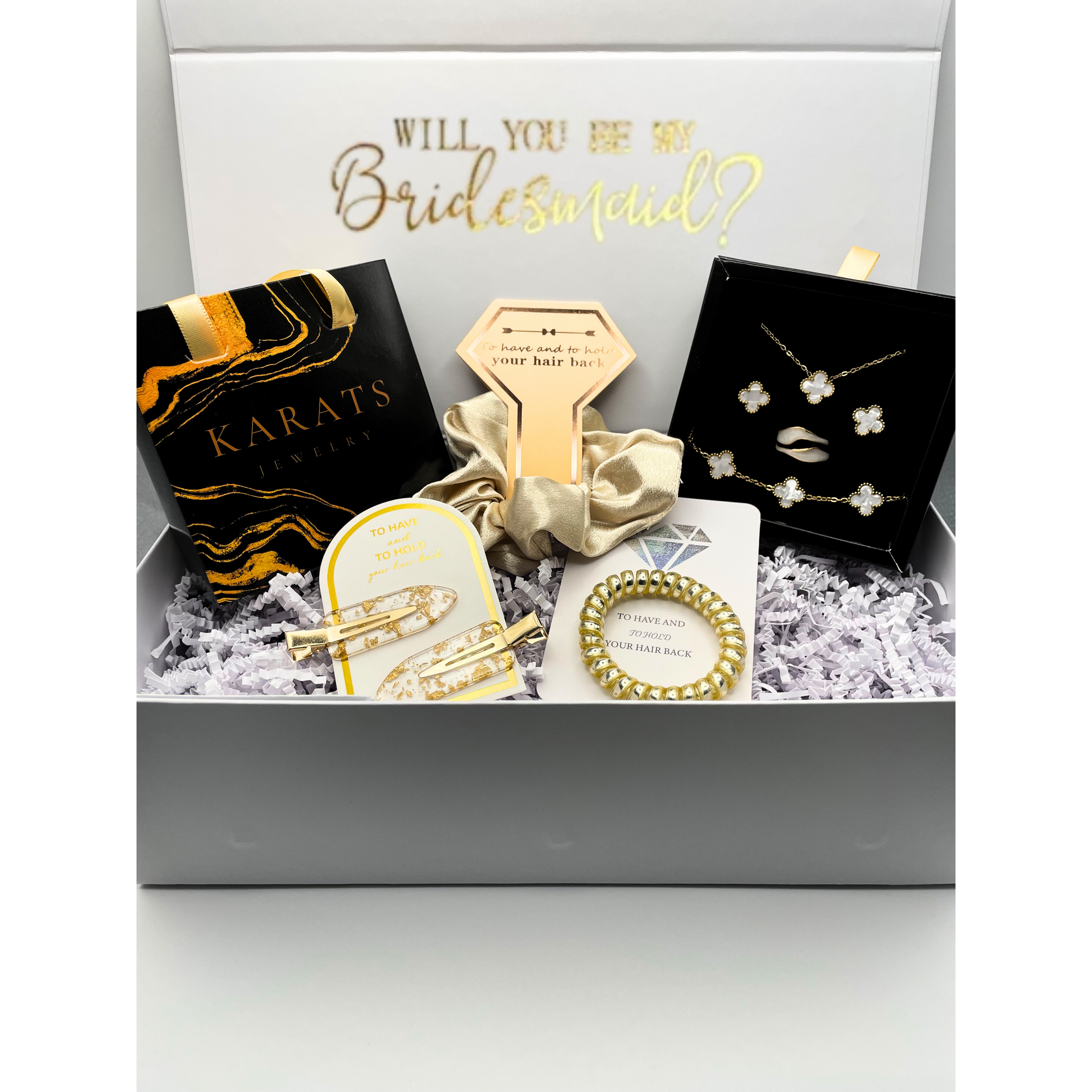 Gift box with jewelry and accessories, including earrings, a bracelet, and necklace, along with a card reading 'Will you be my bridesmaid?' and a box labeled 'Karat's Jewelry'.
