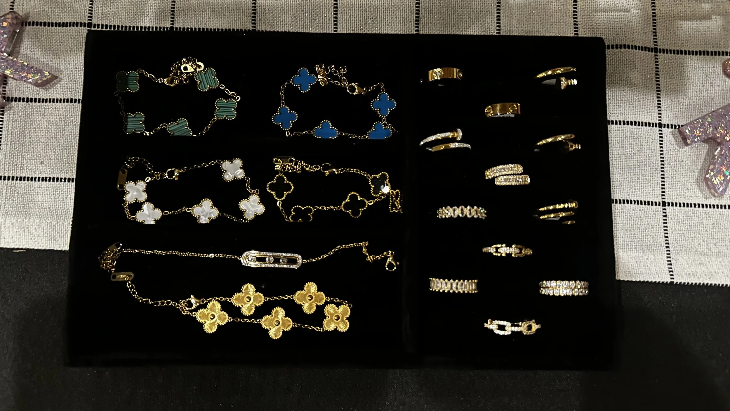A display case with various gold and silver jewelry, including necklaces, bracelets, and rings, on a black velvet surface.