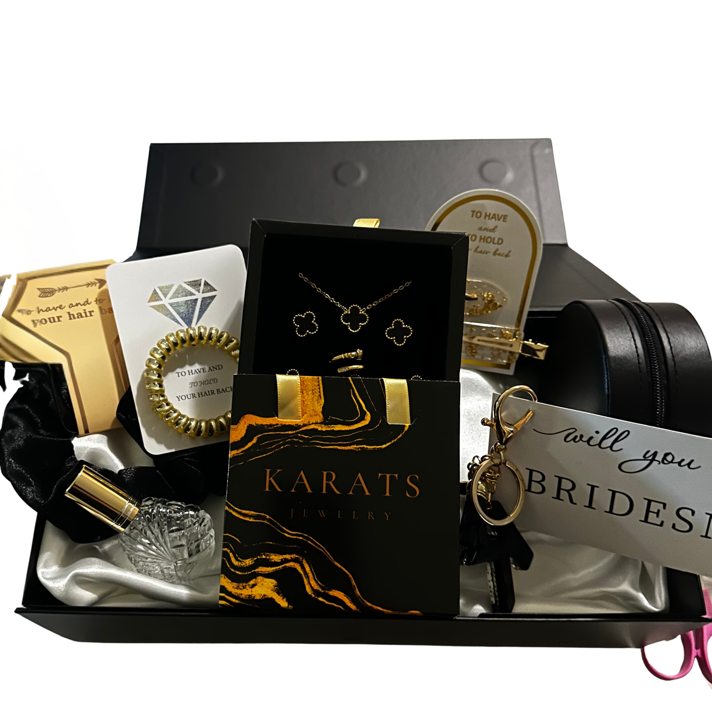 A jewelry gift box containing various jewelry items and accessories, including necklaces, earrings, a bracelet, perfume, and a keychain, arranged on a satin cloth.