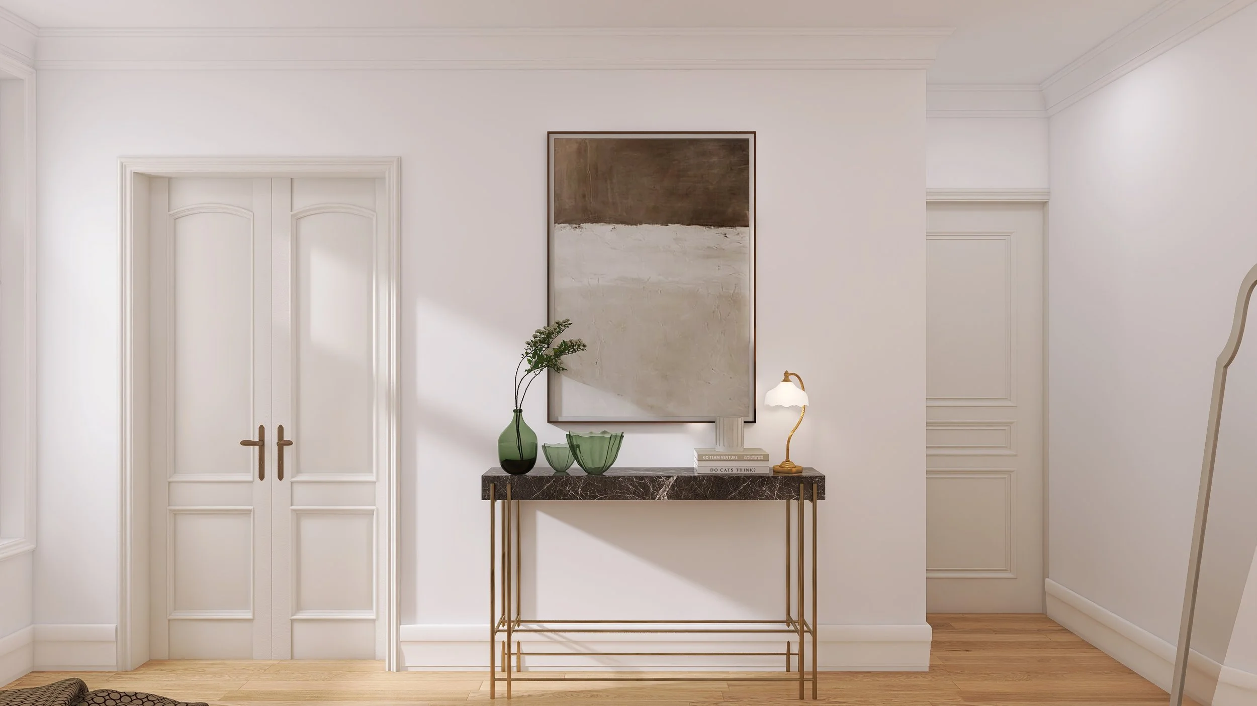Interior scene with white walls, two closed white doors with gold handles to the left, a modern artwork on the wall, a black marble console table with gold legs, decorated with green vases, bowls, a small lamp, and books. The room features crown mold