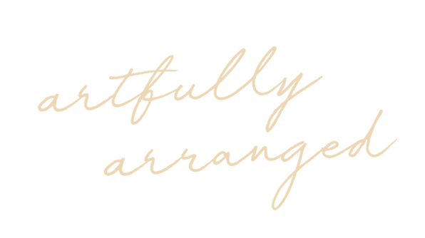 Text that says "artfully arranged" in beige cursive font on a black background.