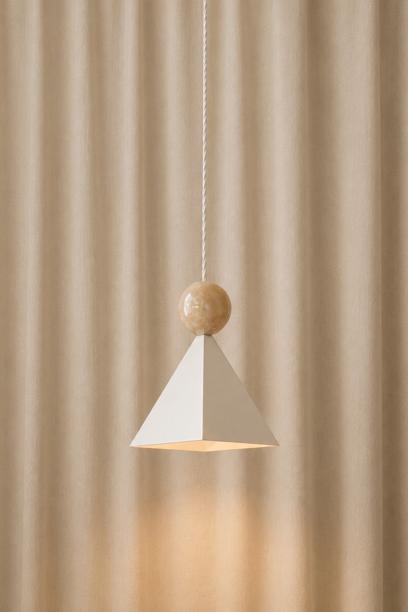 Modern hanging pendant light with a geometric white pyramid-shaped shade, a spherical marble-like decorative element, and a twisted white cord, set against beige curtains.
