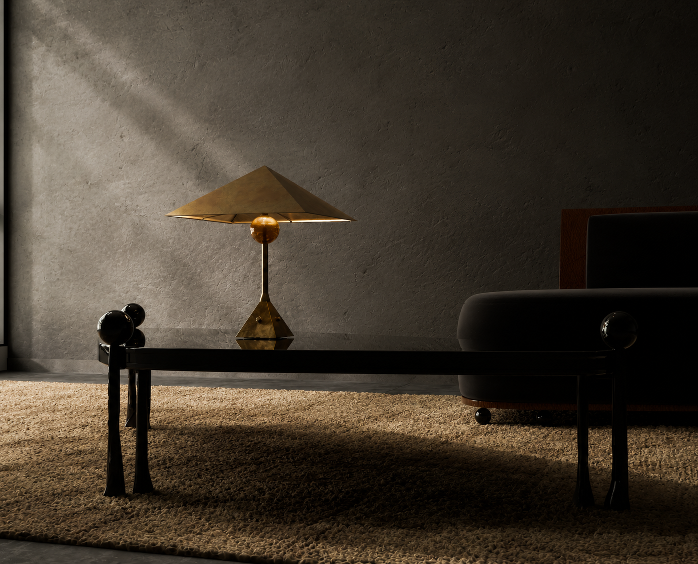 A dark elegant interior room with a black coffee table with spherical accents, a vintage style gold lamp, and a black armchair with a rounded armrest. A textured beige rug covers the floor, and the wall behind has a subtle textured gray finish.