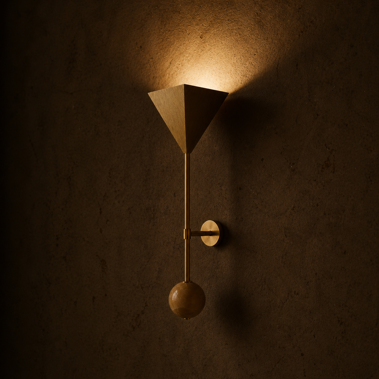 Modern wall sconce with a geometric, cone-shaped shade emitting warm light, mounted on a textured brown wall.