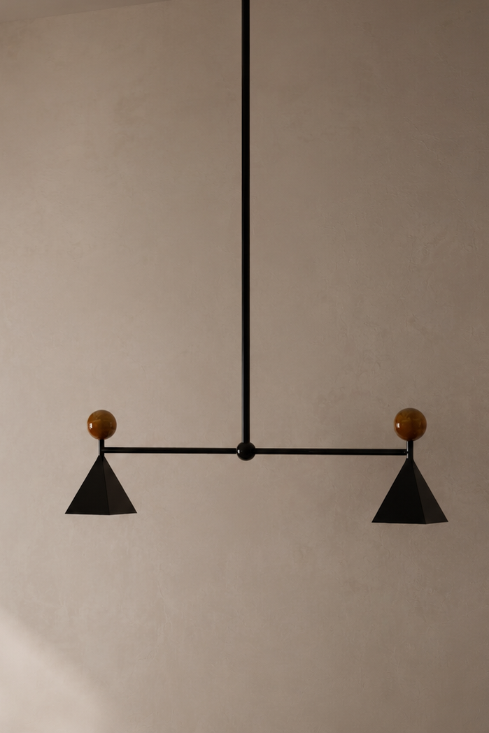 Modern black and brown ceiling light fixture with two geometric cone-shaped shades, mounted on a neutral beige ceiling.