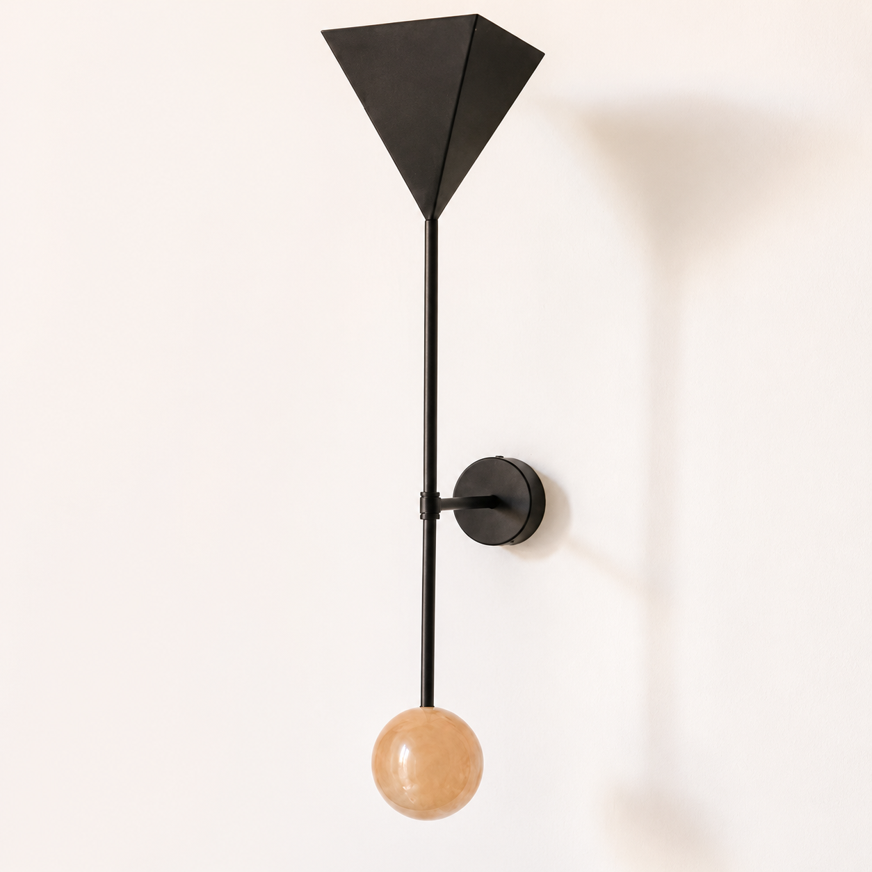 Modern black wall-mounted light fixture with a spherical beige bulb hanging below.