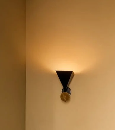 Wall sconce with light bulb on beige wall.