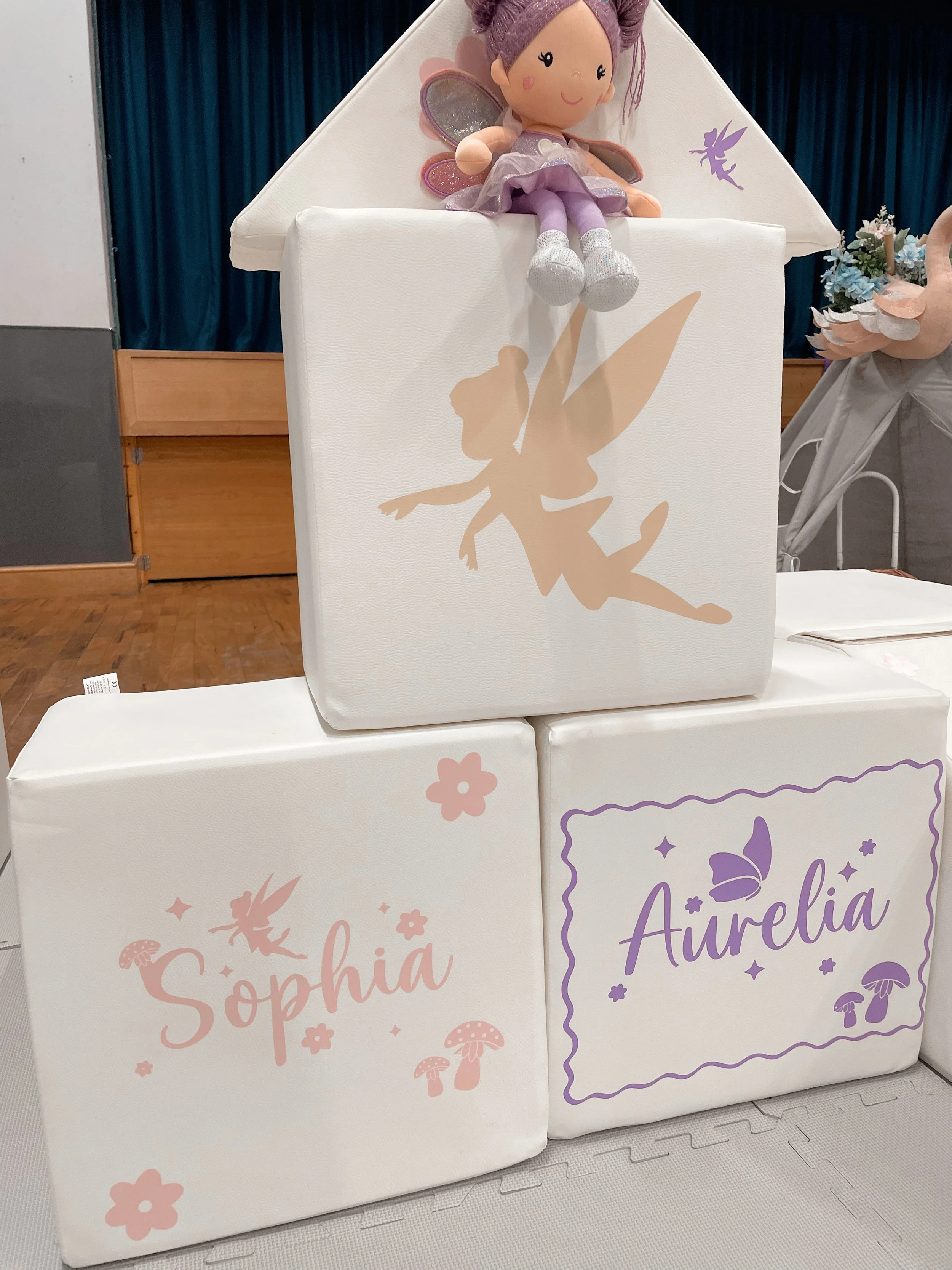 Decorative display with plush fairy doll on top and blocks labeled 'Sophia' and 'Aurelia' with fairy and mushroom illustrations.