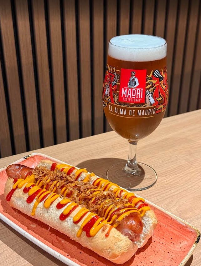 Hot dog with mustard and ketchup, and a Madri beer available from the extensive food and drink menu at Hickey's & Friends bar in Barnoldswick, Lancashire.
