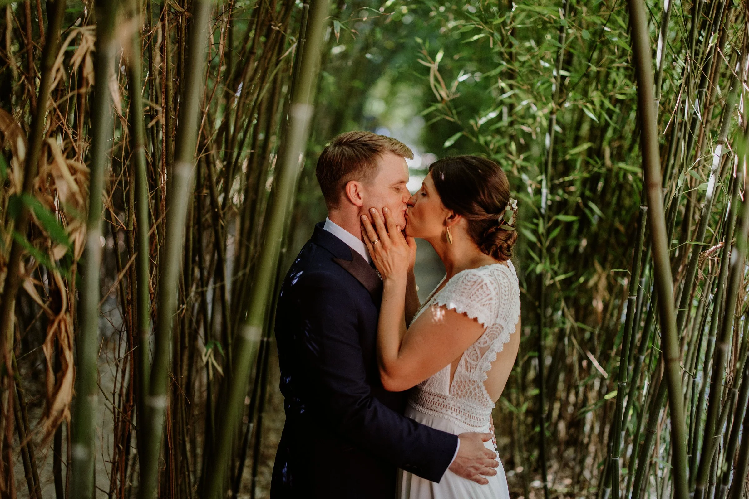Ein Hochzeitspaar küsst sich umgeben von Bambus im Wald.