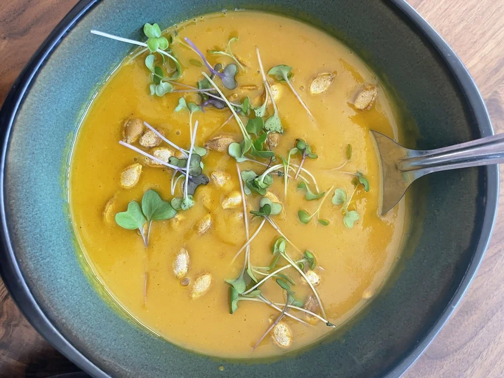 Soup in green bowl topped with microgreens and seeds