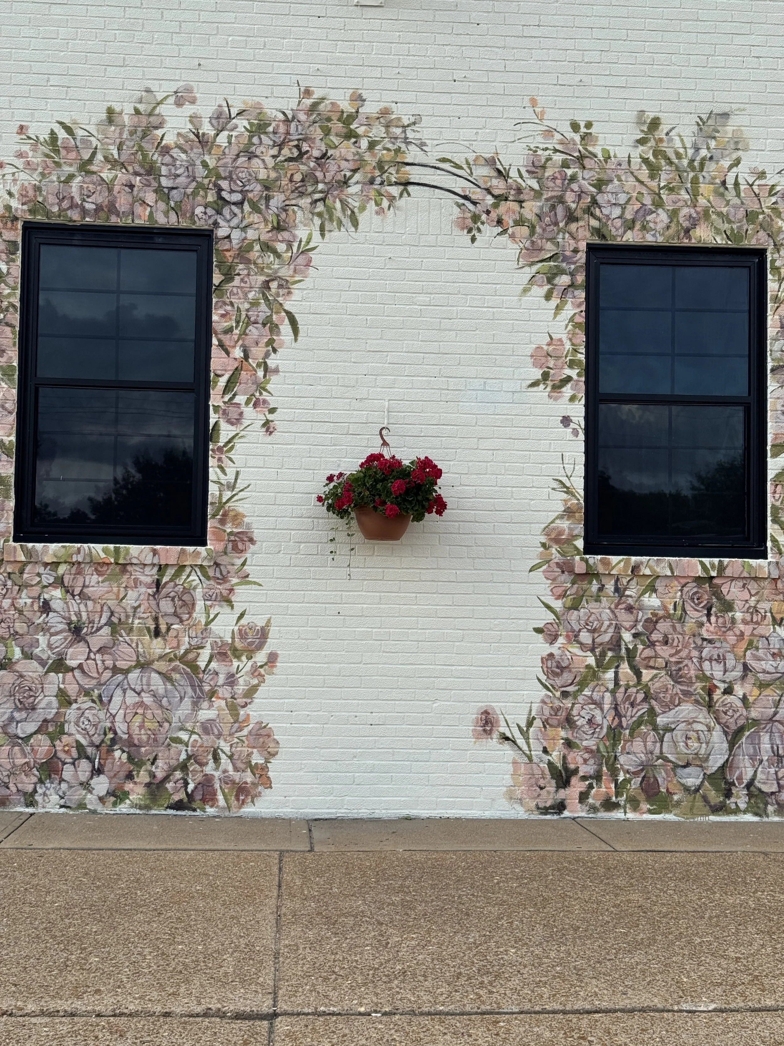 Mural on outside of a building with many flowers in pink that form the shape of an arch