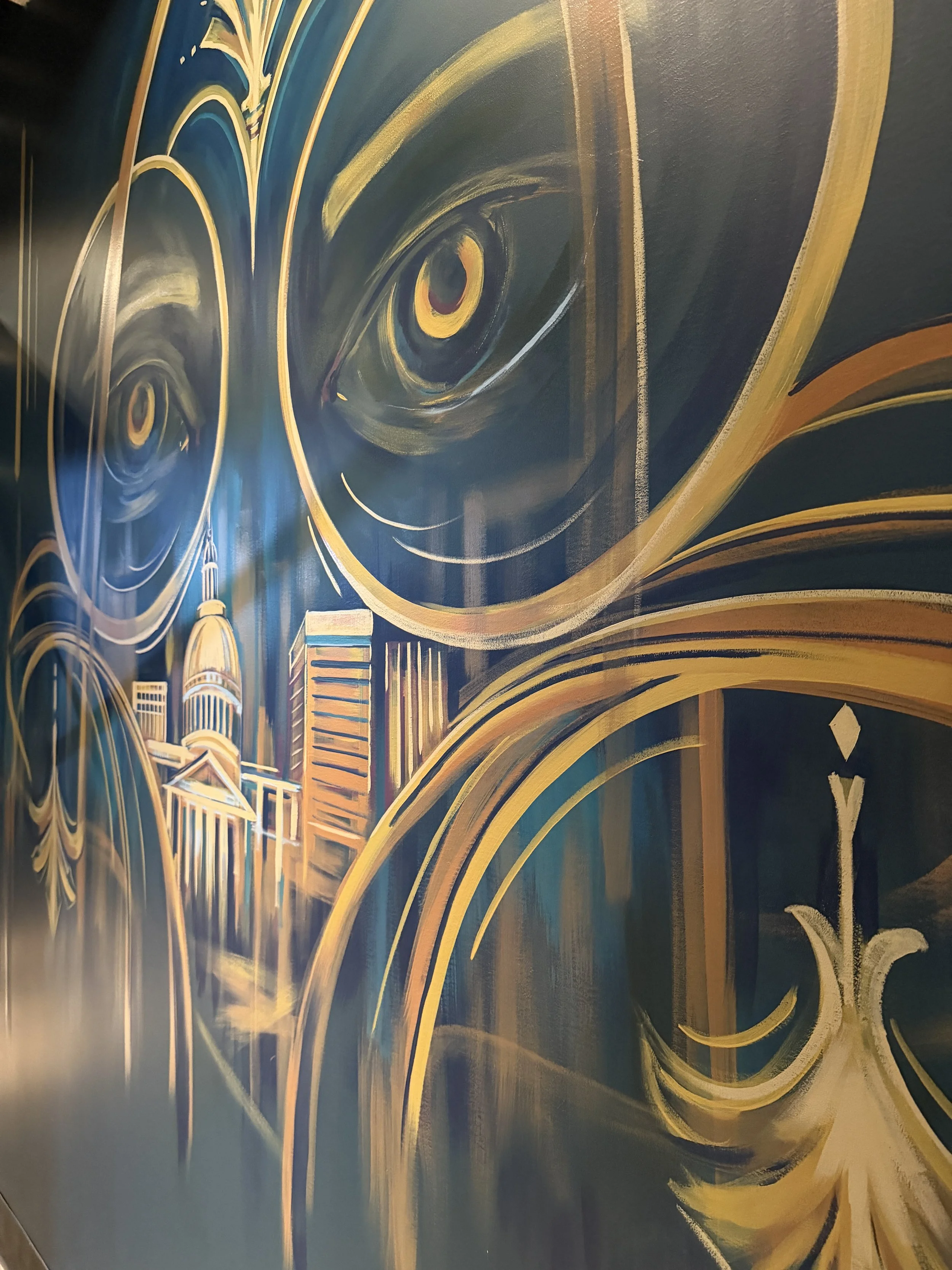 Mural depicting two eyes and a city in gold