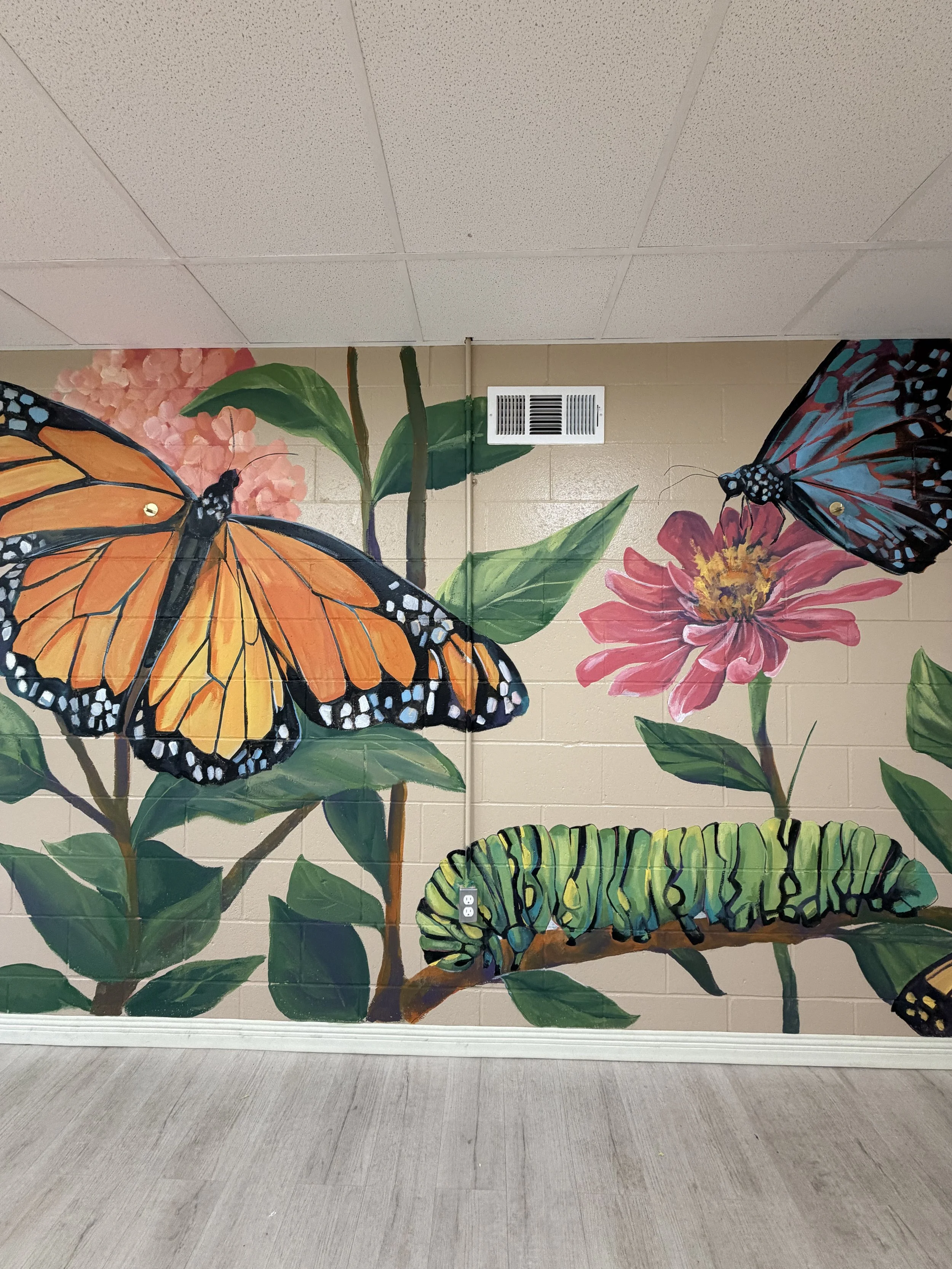 Mural on wall of caterpillar, butterflies, flowers, and leaves