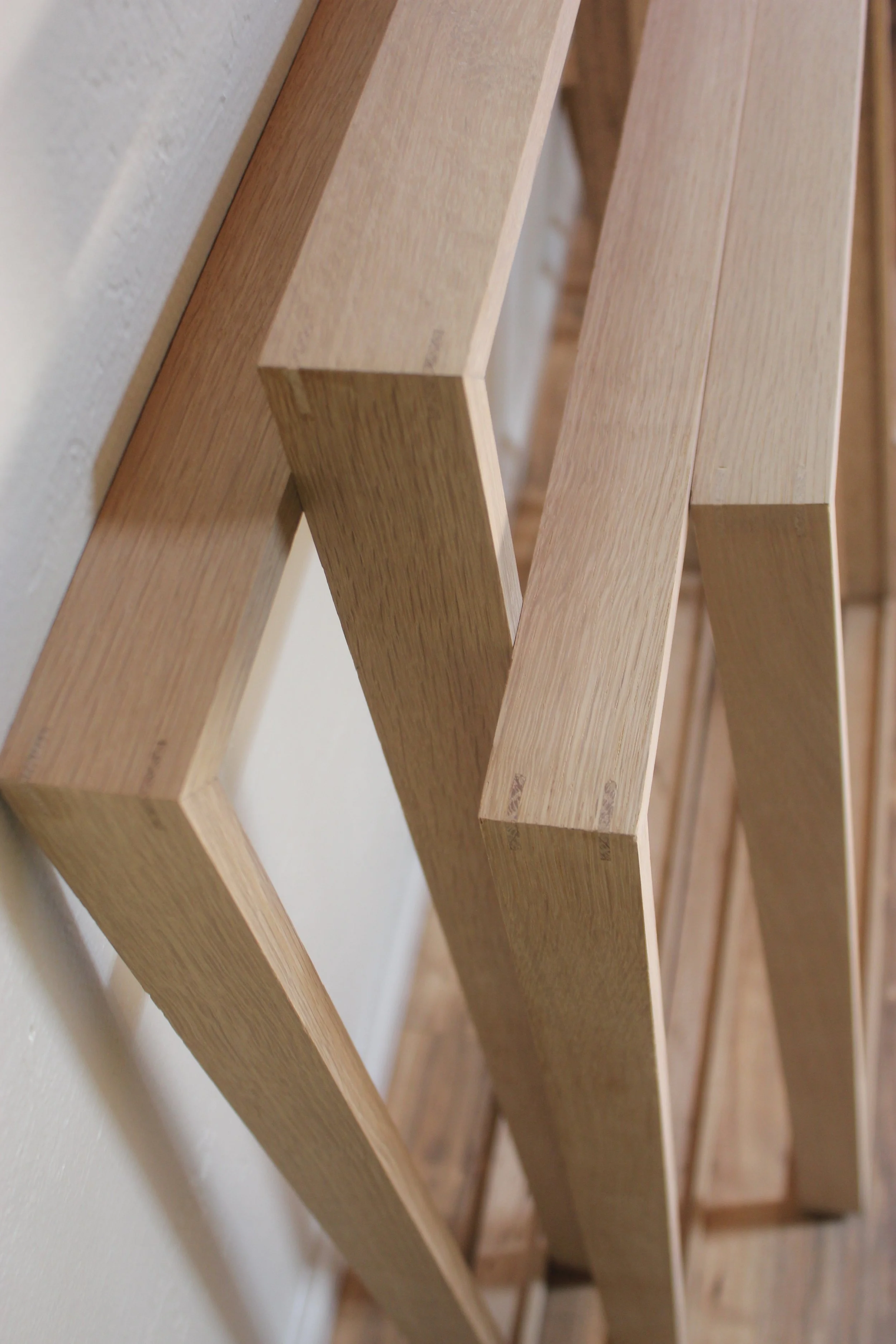 Four gallery frames made of rift sawn white oak shown in a home setting. Each frame features mitered corner joinery reinforced by visible splines, which add beauty as well as strength to the frame.