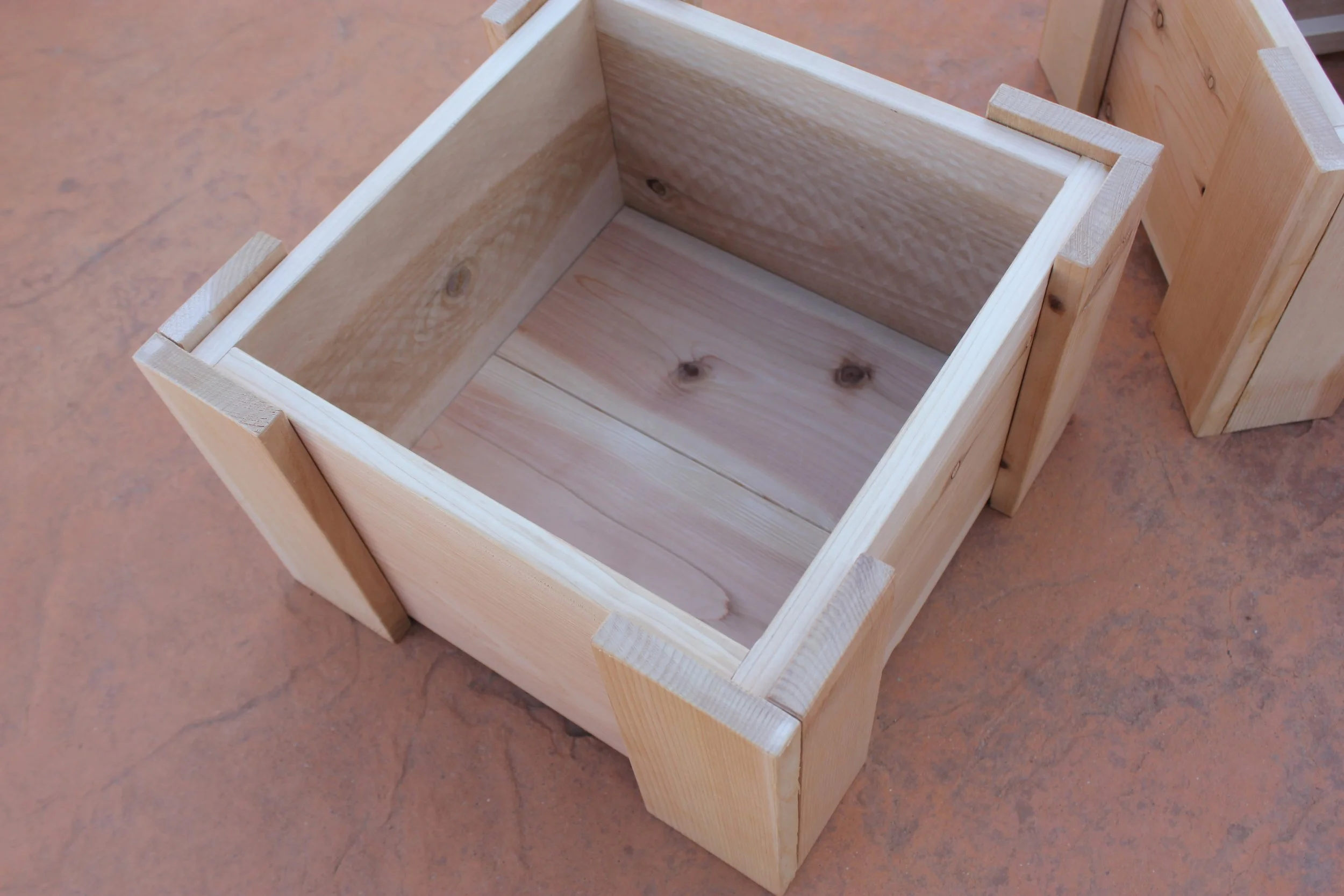 Detail of the interior of a cedar mini planter box against a patio background.